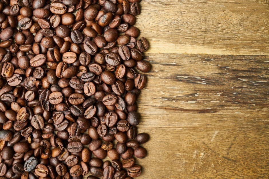 Top view of shiny aromatic roasted coffee beans scattered on rustic wooden table