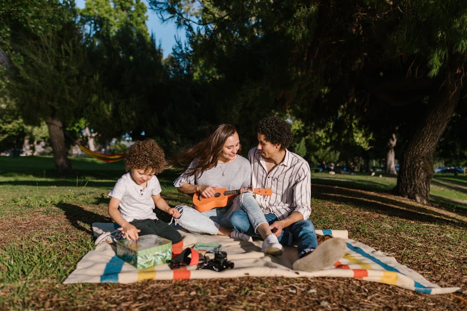 Family with a Little Son Having a Picnic in the Park and Woman Playing on Ukulele