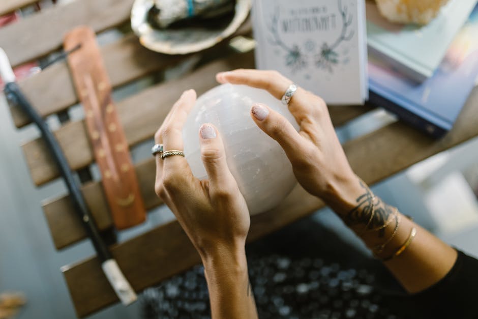 Hands Holding the Crystal Ball on the Wooden Table