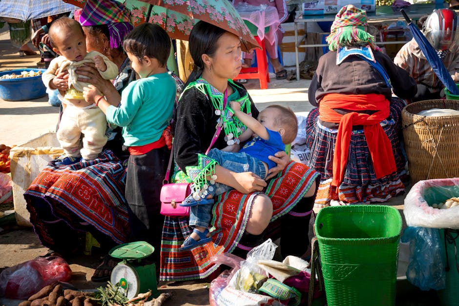 Unrecognizable ethnic sellers in traditional clothes with kids against fresh vegetables in local bazaar on sunny day