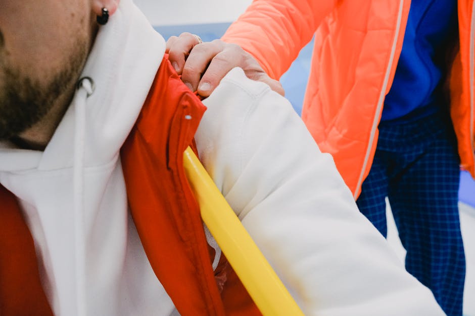 Closeup of hand of trainer on shoulder of male member of sport team while supporting sportsmen in competition