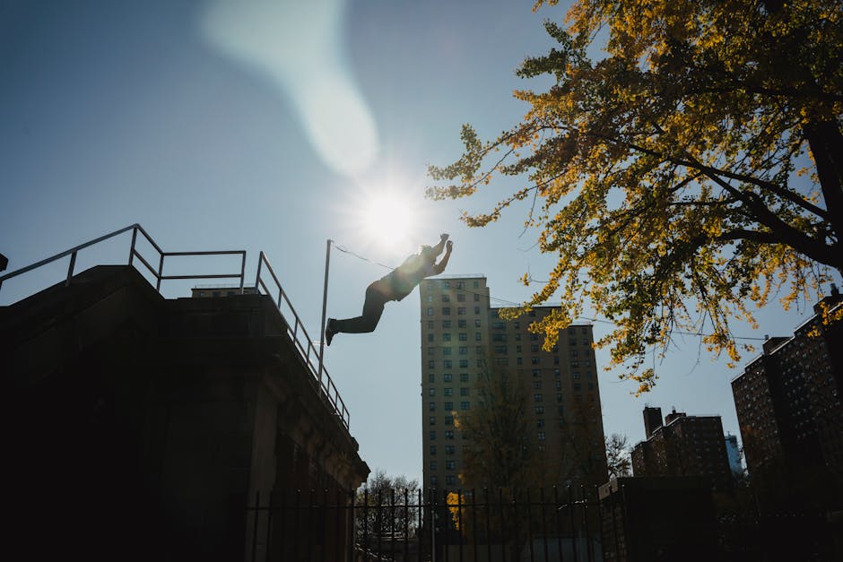 Silhouette of anonymous male athlete performing trick while practicing parkour under bright sunlight