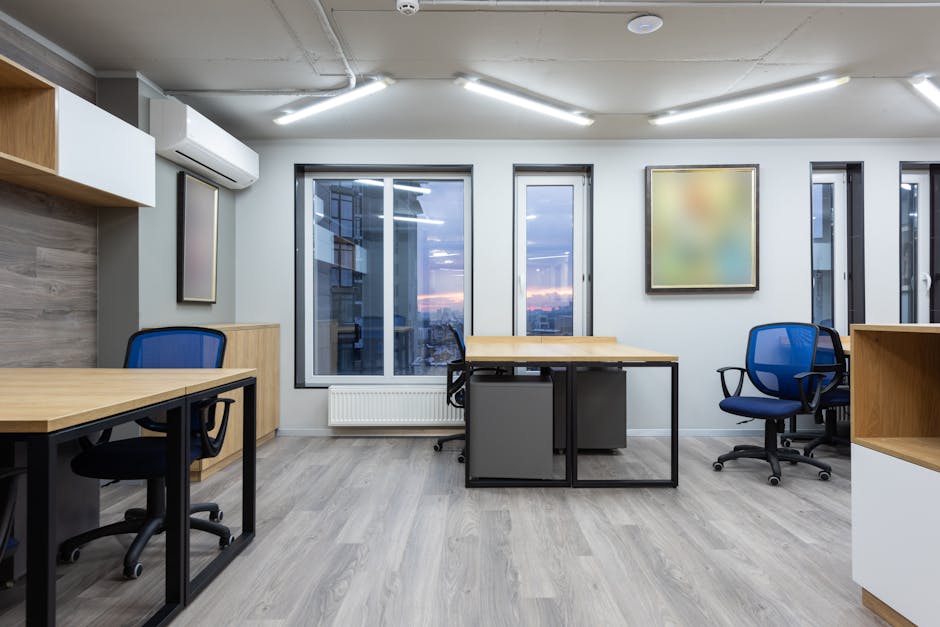 Interior of cotemporary office with wooden tables and chairs illuminated by ceiling lamps