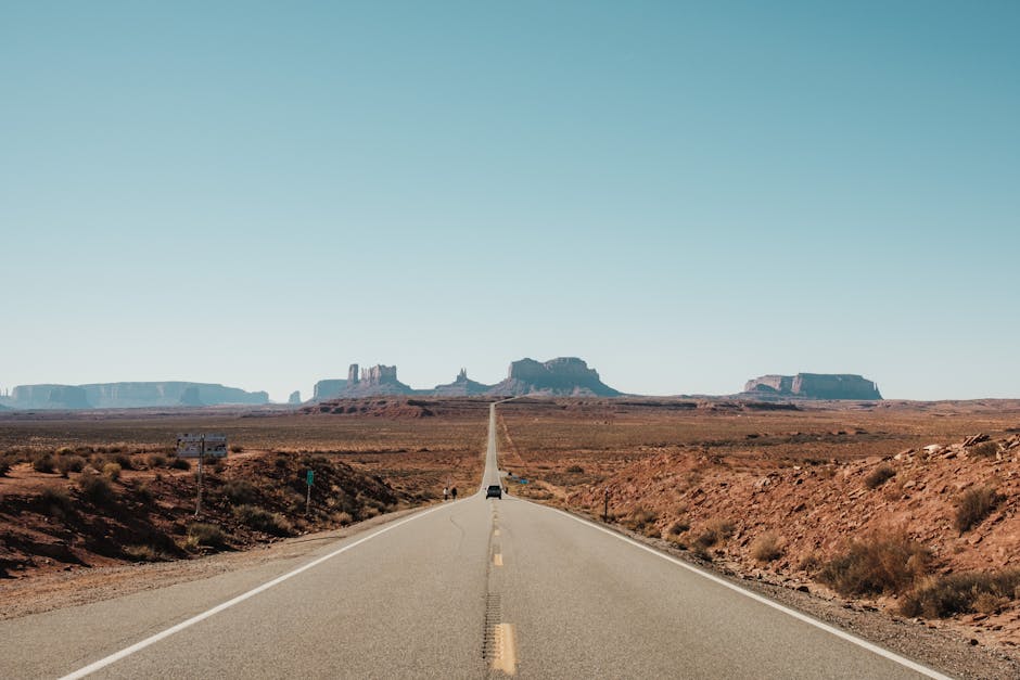 A long empty road with a desert landscape in the background