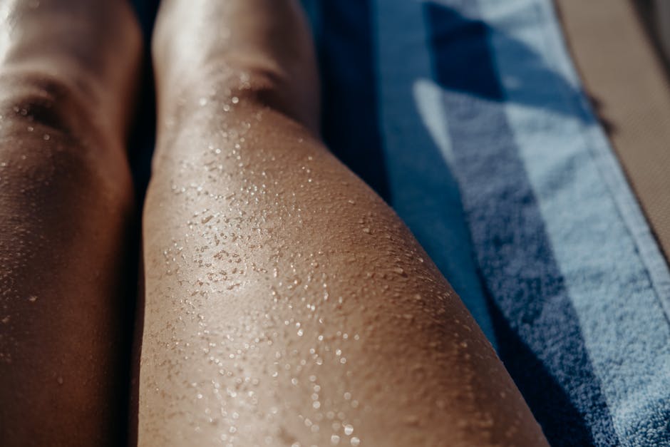 Close-up of Wet Legs of a Person Sitting on a Towel on a Beach