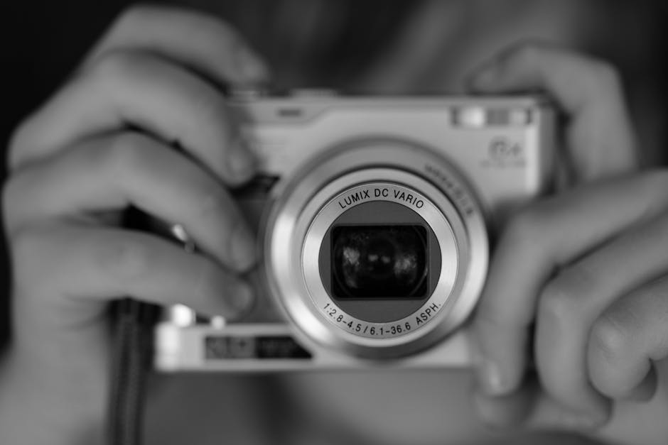 A person holding a camera in black and white