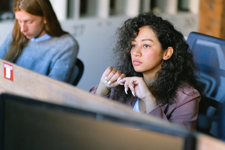 High angle of concentrated female employee sitting at table in open space and thoughtfully looking away