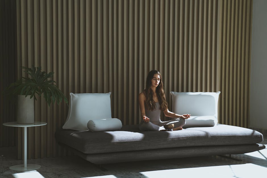 A Woman Sitting on the Couch while Meditating with Her Eyes Closed