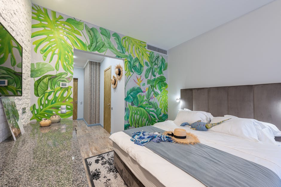 Comfortable bed with straw hat placed in hotel suite with decorations and green painted wall during trip in tropical country
