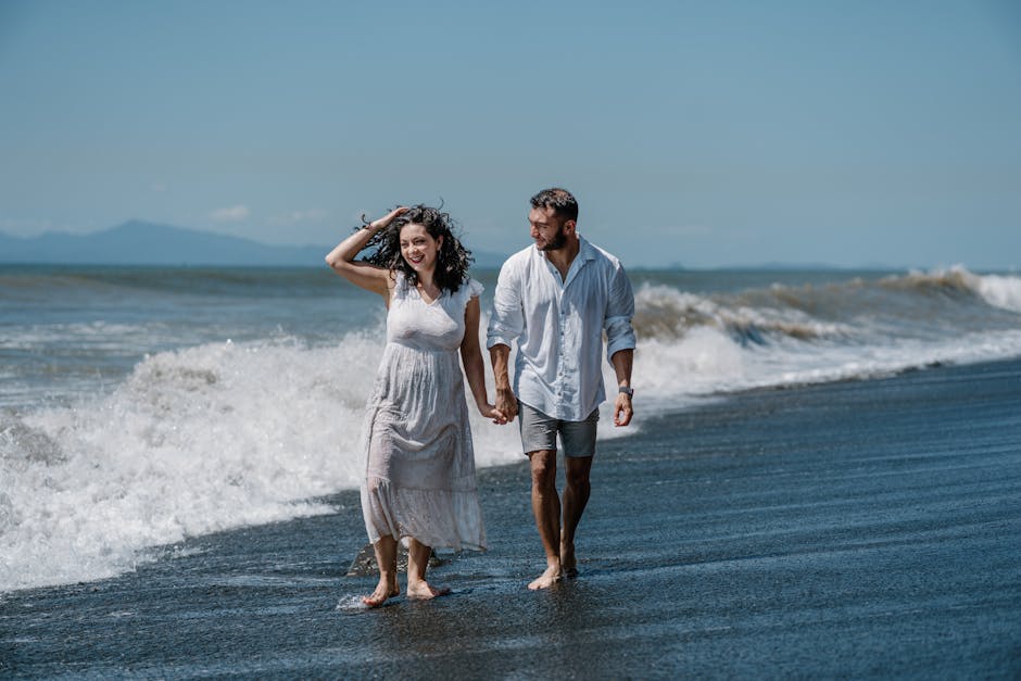 A man and woman walking on the beach in front of the ocean