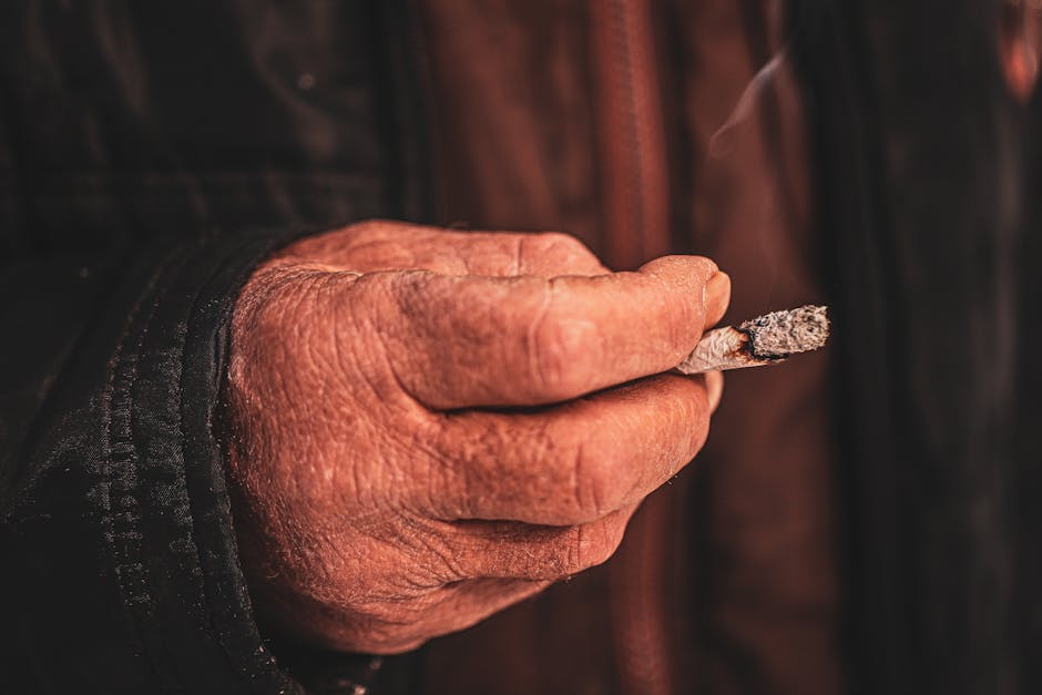 An old man is holding a cigarette in his hand