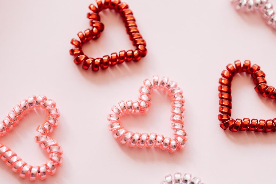 Colorful hair ties in shape of hearts on pink surface