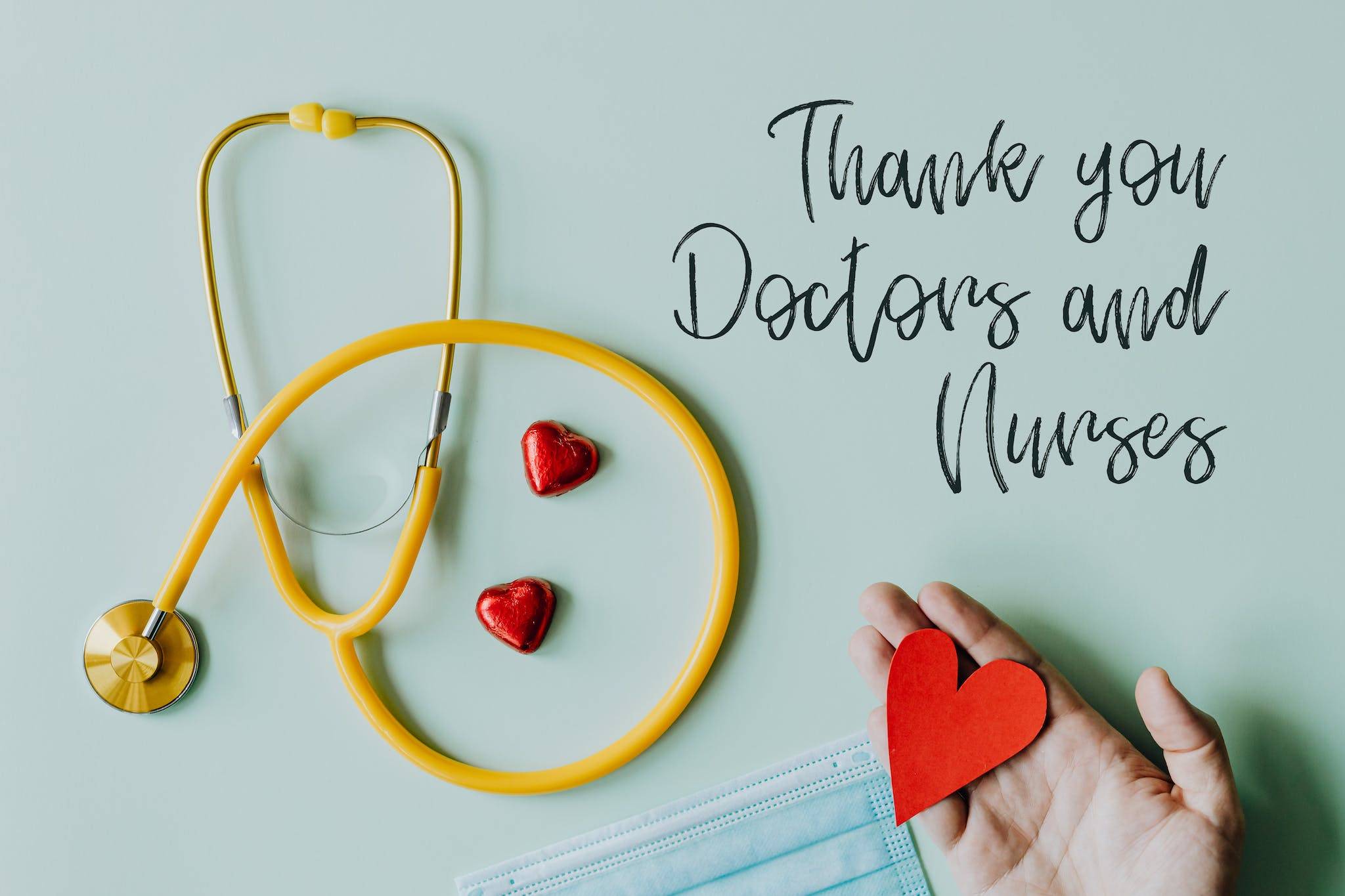 Yellow stethoscope composed with red hearts on white background with thank you doctors and nurses text and medical mask