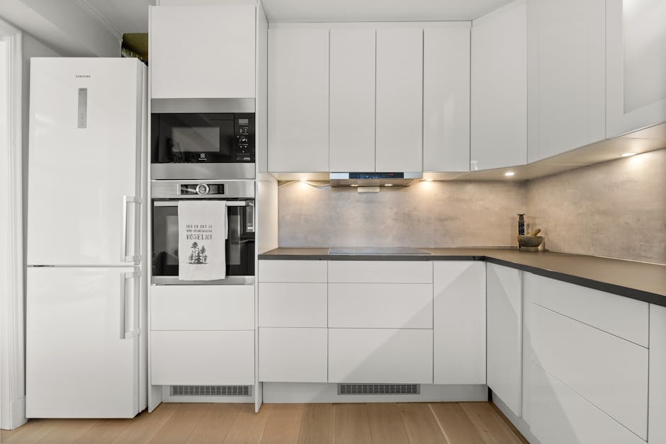A white kitchen with a refrigerator, microwave and stove