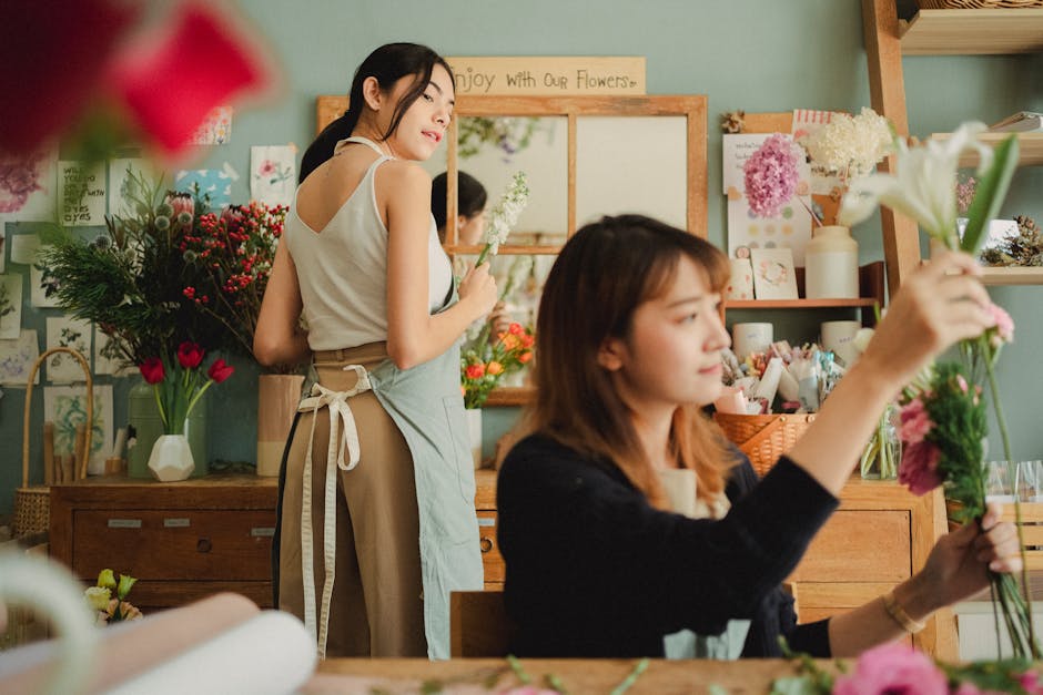 Focused multiethnic women in aprons working in cozy floral shop with various fresh flowers