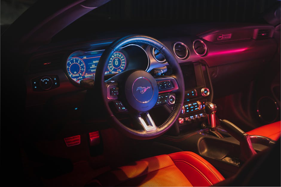 Interior of contemporary car with glowing dashboard and computer behind steering wheel and leather seats