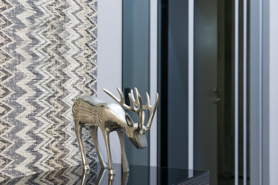 Decorative metal animal statuette with horns reflecting on table against ornamental wall at home