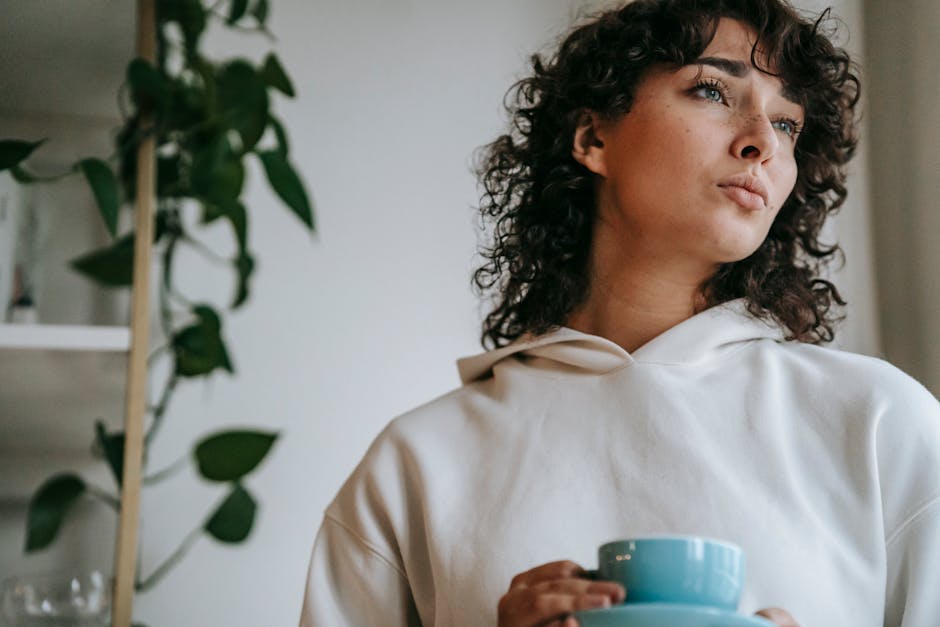 Pensive woman with hot beverage at home