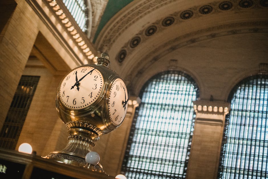 From below of vintage golden clock placed in hallway with aged interior with ornamental walls and windows and high ceilings placed in Grand Central Terminal in New Your City in daytime