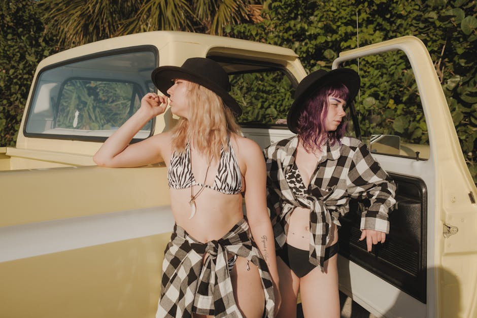 Two women in bikinis standing next to a truck