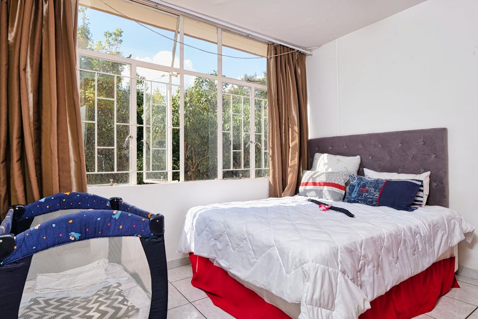 A bedroom with a bed, a window and a large red curtain