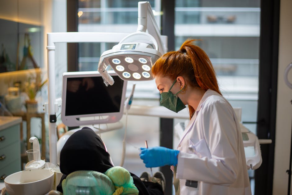 A woman in a mask and gloves is working on a patient