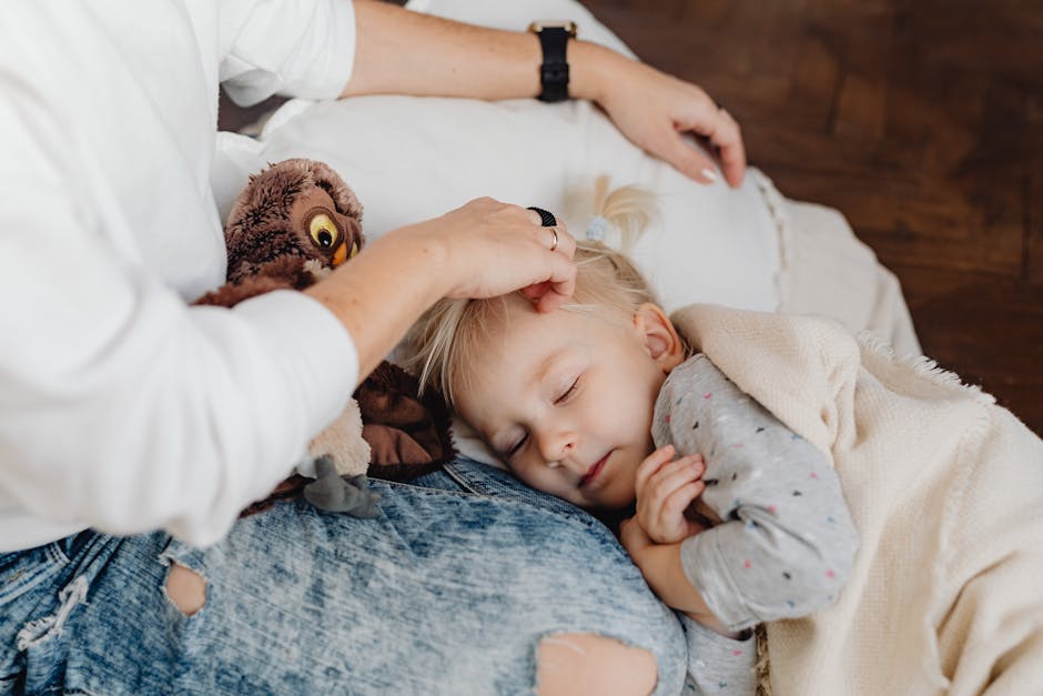 Woman in White Sweater and Denim Jeans Stroking Hair of a Girl in Gray Shirt Sleeping Beside Her