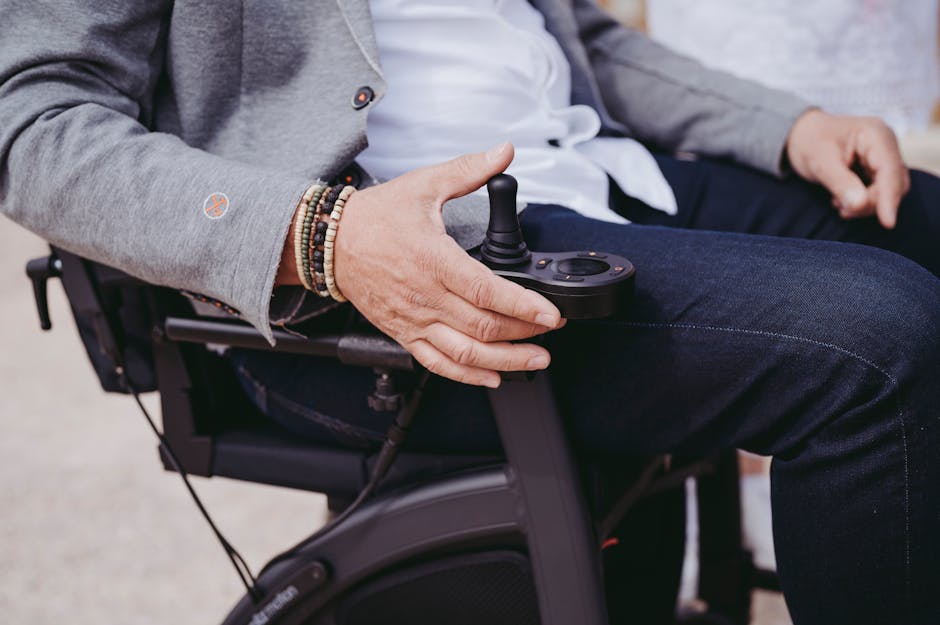 Elegant Man Sitting in Electric Wheel Chair with a Joystick Controller