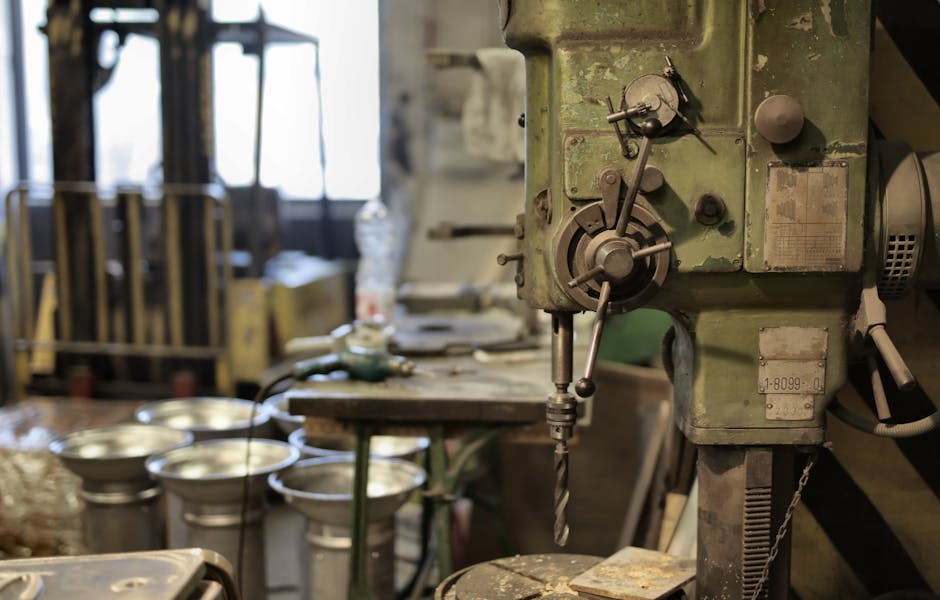 Side view of industrial drilling machine with green casing situated in deserted workshop