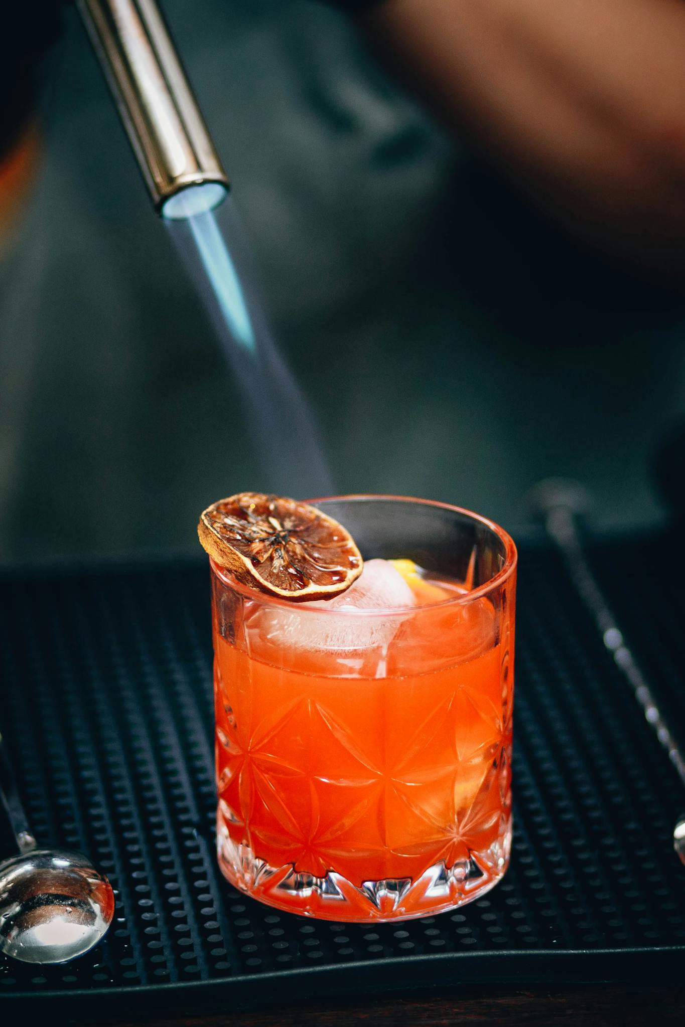 Bartender burning citrus slice on cocktail