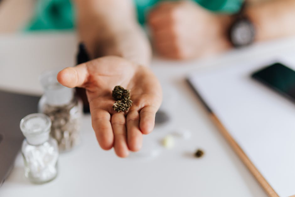 Faceless medical worker showing sample of herbal medicine in hand while sitting at table