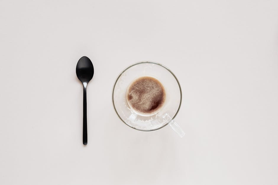 Cup of coffee and teaspoon on beige background