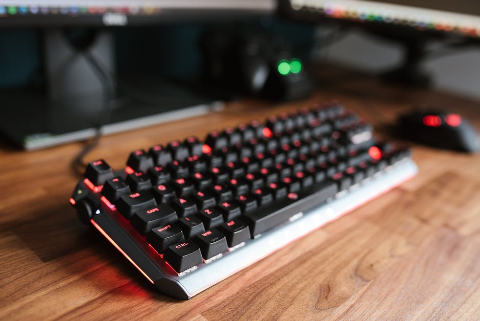 Contemporary computer backlit keyboard placed on wooden desk near mouse in light room