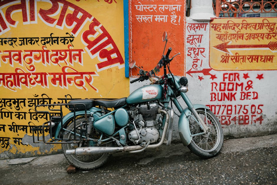 Old rusty motorcycle parked near shabby wall with various graffiti and inscriptions on city street