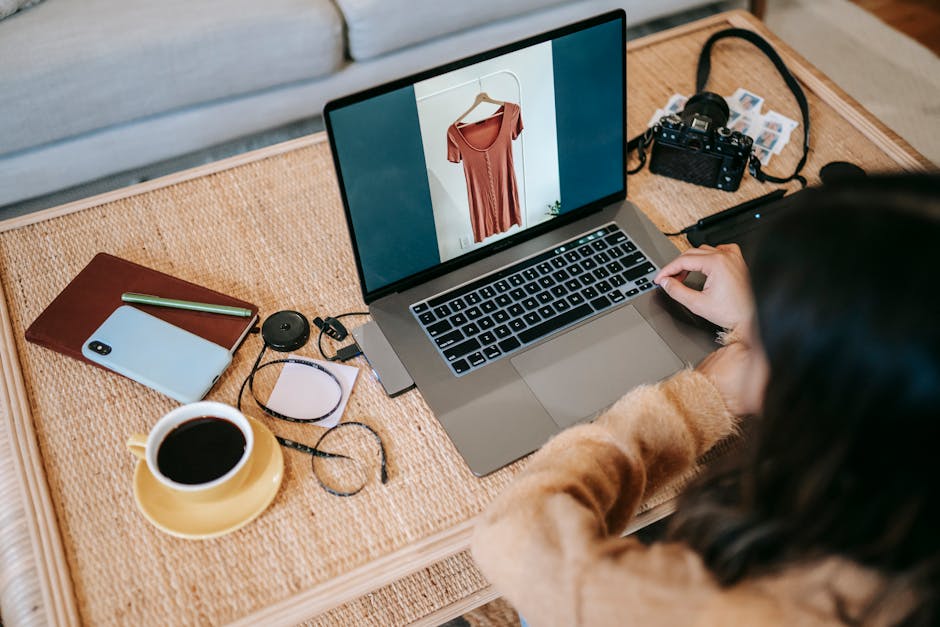 Desde arriba, vista posterior de una empleada remota anónima que muestra fotografías en la pantalla del netbook en la mesa con una bebida caliente