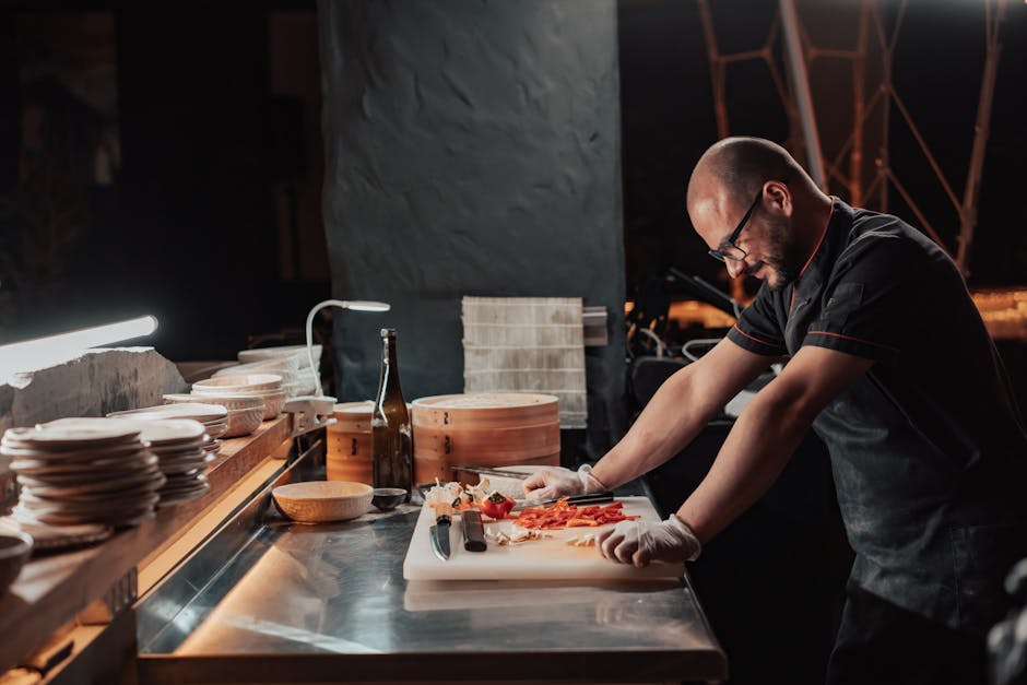 Man in Black Chef Uniform Standing by the Chopping Board