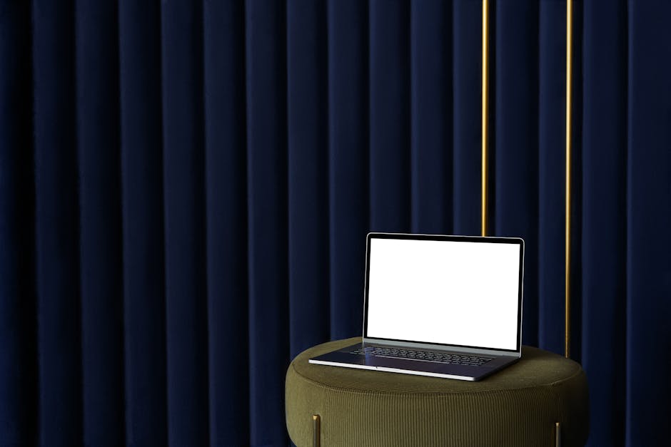 Laptop placed on pouf near curtain