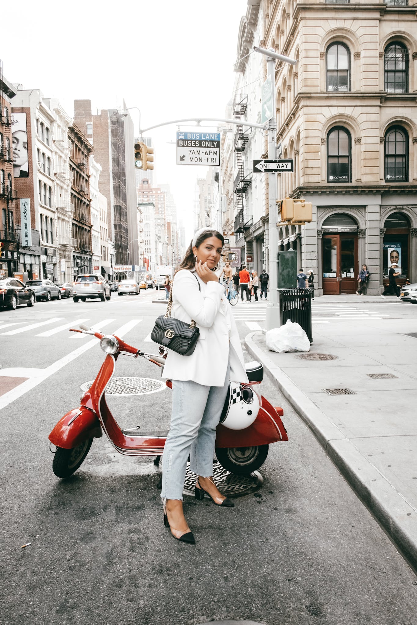 Young happy female in trendy outfit on asphalt road of street with modern buildings