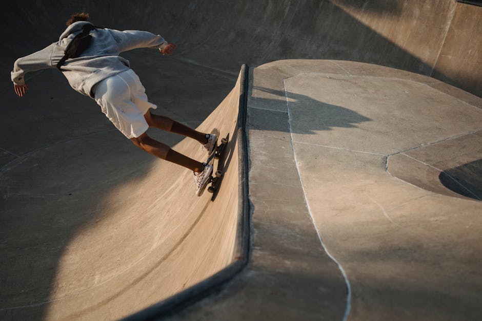 From above back view of unrecognizable sportsman balancing on skateboard on ramp in soft sunlight