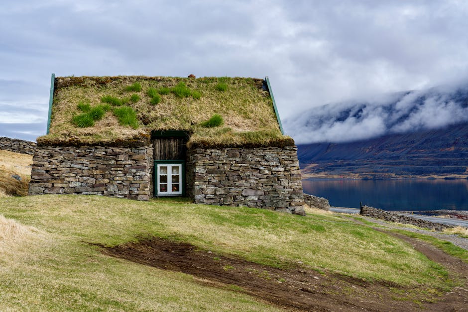 A small stone house with grass roof and grass on the roof