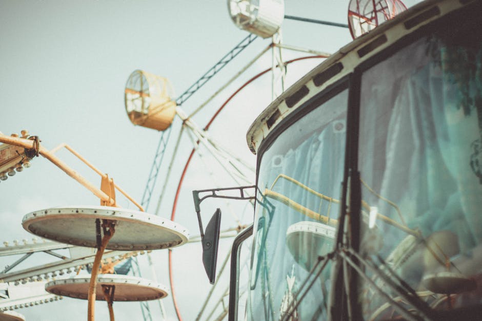 Modern bus parked against Ferris wheel and cloudless blue sky in amusement park in city