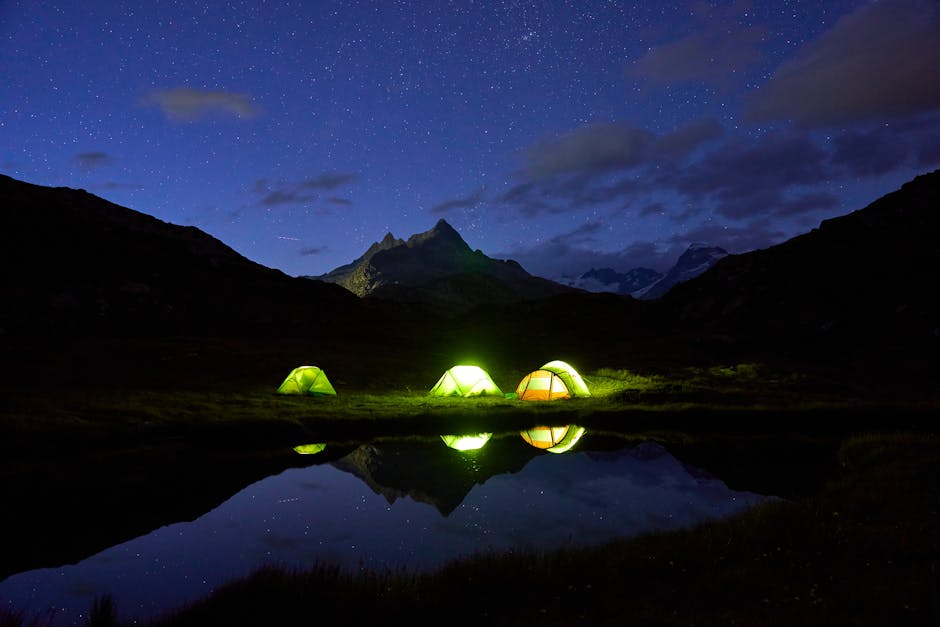 A night scene with tents lit up in the mountains