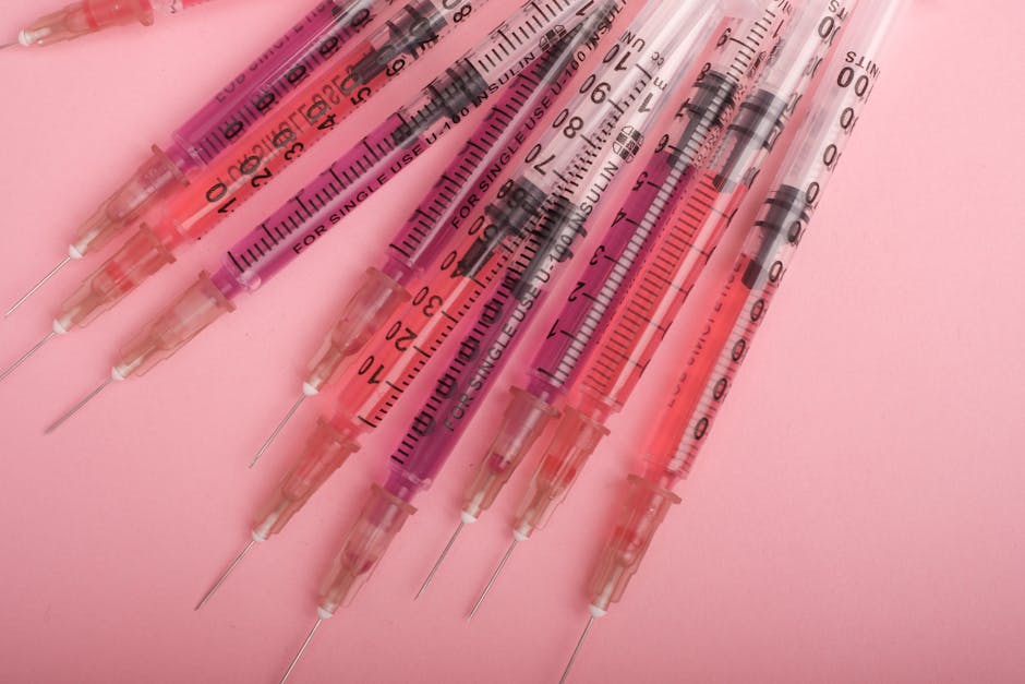Set of syringes with liquid drug arranged on pink background