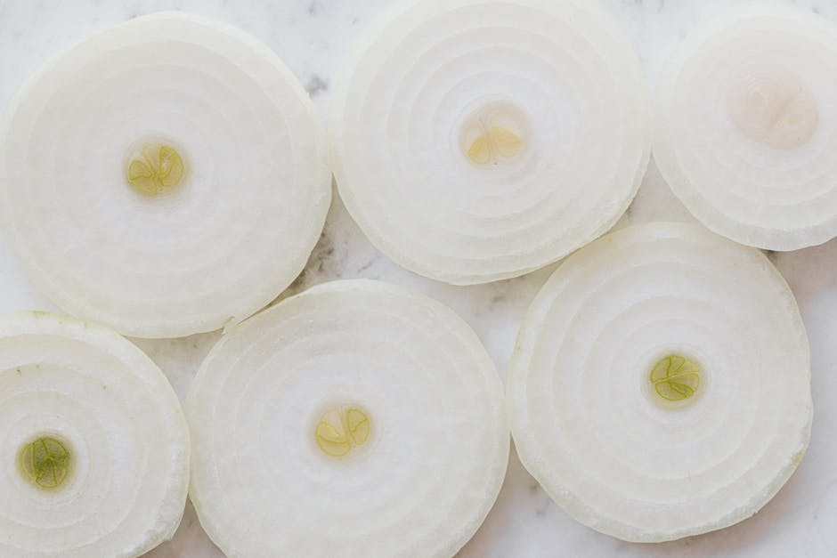 Top view closeup of ripe organic yellow peeled onion cut into rings and placed on white marble tabletop