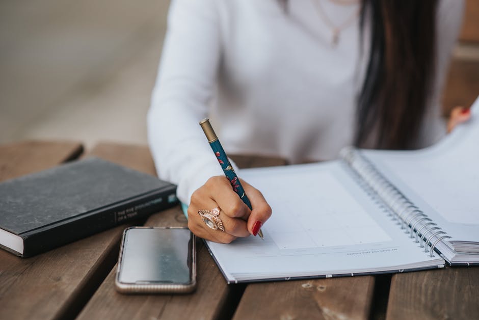 Crop office employee taking notes in notebook at table