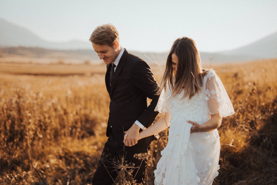 Shallow Focus Photo of Man in Black Formal Suit Holding Woman’s Hand in White Dress