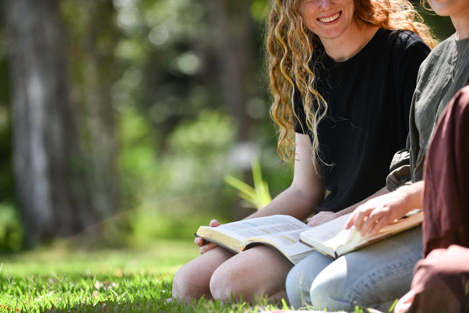 Two women sitting on the grass reading books