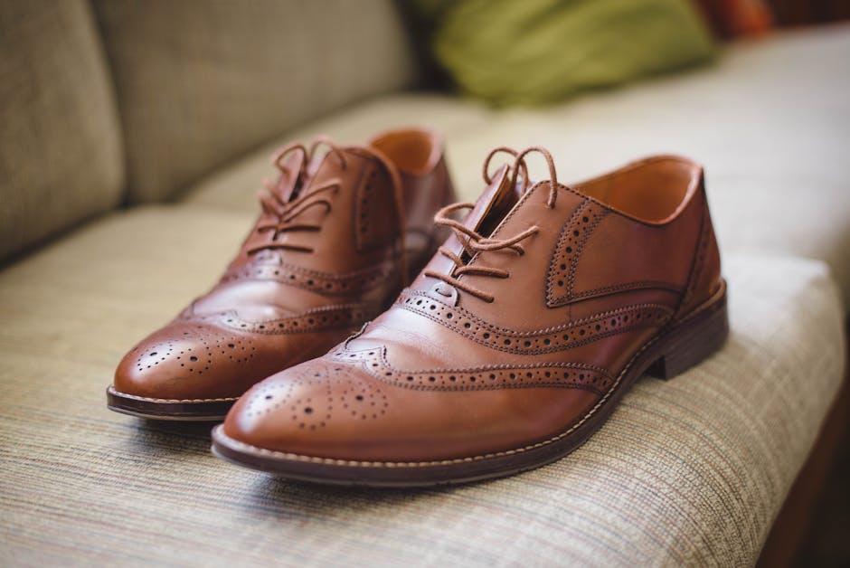 Elegant brown pair of leather shoes for men placed on gray surface at home