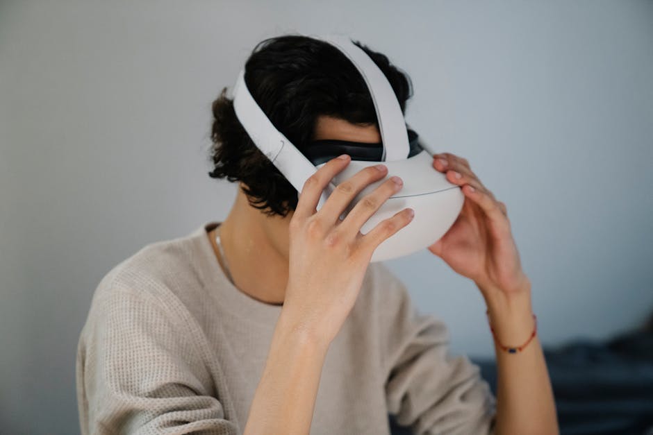 Unrecognizable young guy putting on modern VR glasses against gray wall at home