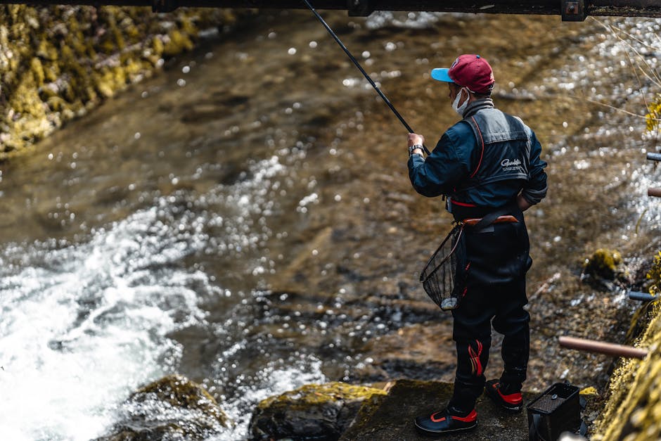 A man fishing on a riverbank with a rod